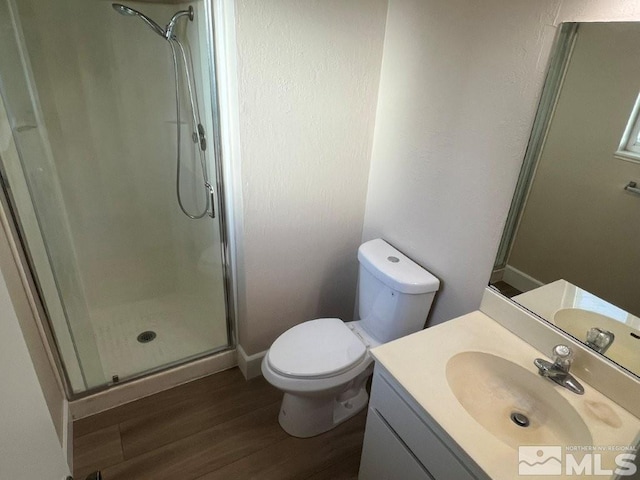 bathroom featuring hardwood / wood-style floors, vanity, toilet, and a shower with door