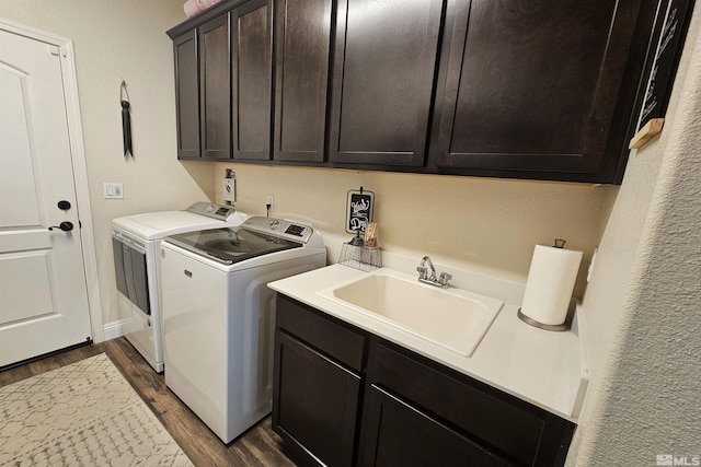 clothes washing area featuring sink, dark wood-type flooring, cabinets, and washer and clothes dryer