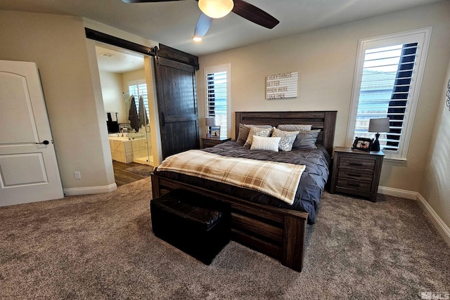 carpeted bedroom with ensuite bath, ceiling fan, and a barn door