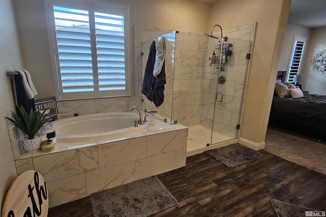 bathroom with wood-type flooring, a healthy amount of sunlight, and separate shower and tub