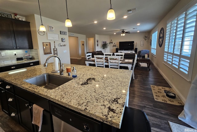 kitchen with stainless steel dishwasher, hanging light fixtures, a center island with sink, ceiling fan, and sink