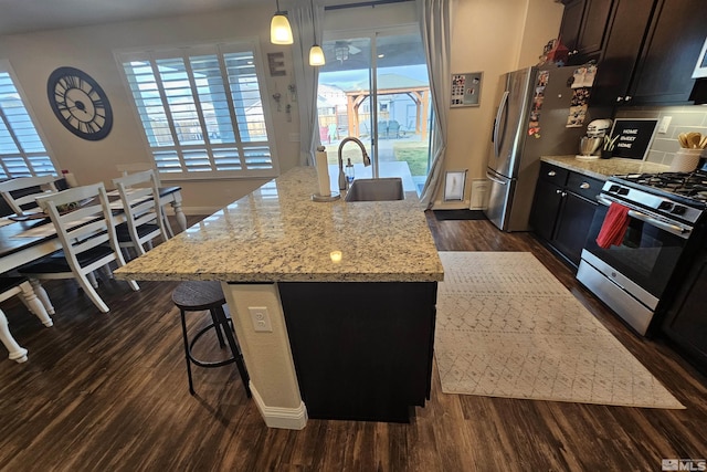 kitchen featuring hanging light fixtures, a kitchen island with sink, and stainless steel appliances