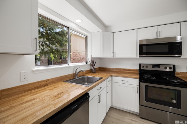 kitchen featuring sink, white cabinets, stainless steel appliances, and wood counters