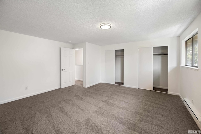 unfurnished bedroom featuring two closets, a textured ceiling, a baseboard radiator, and dark carpet