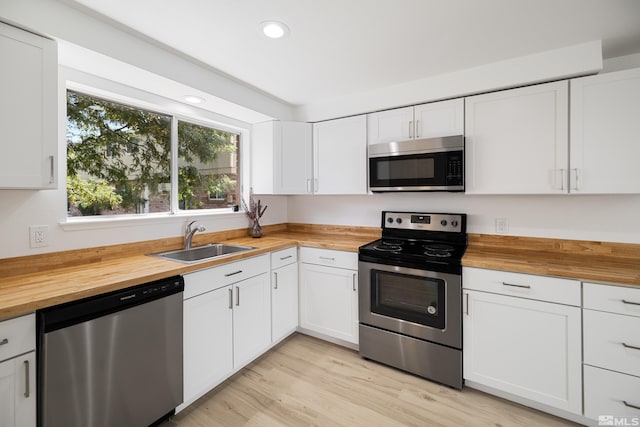 kitchen with sink, white cabinets, wooden counters, and appliances with stainless steel finishes