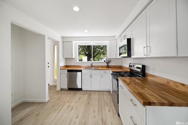 kitchen with white cabinets, light hardwood / wood-style floors, appliances with stainless steel finishes, and wooden counters