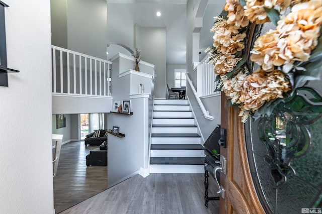 stairway featuring wood-type flooring and a towering ceiling