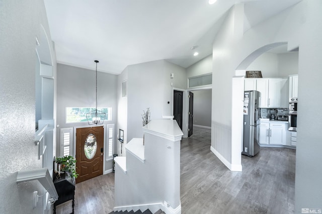 foyer with hardwood / wood-style floors, high vaulted ceiling, and a notable chandelier