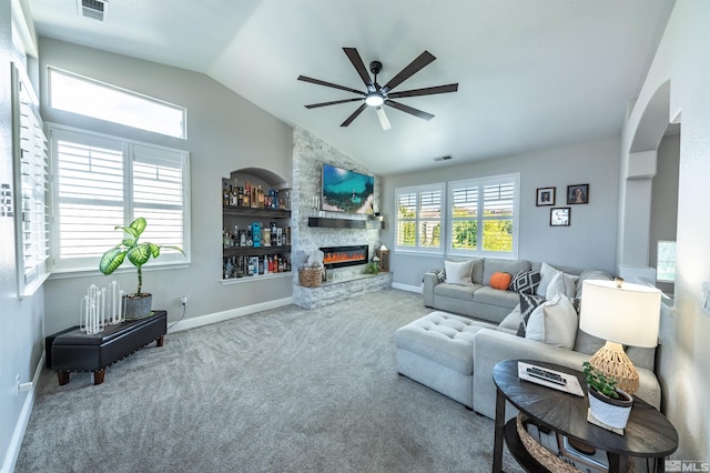 carpeted living room with a fireplace, built in shelves, ceiling fan, and lofted ceiling