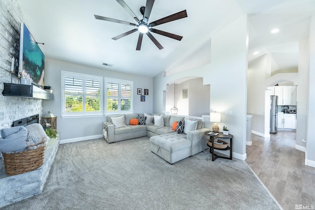 living room with ceiling fan, a fireplace, high vaulted ceiling, and light hardwood / wood-style floors