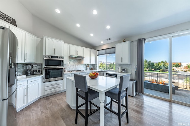 kitchen featuring backsplash, stainless steel appliances, vaulted ceiling, sink, and white cabinets