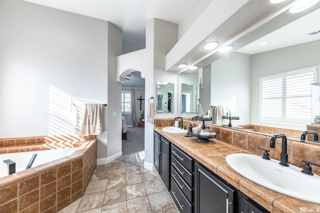 bathroom with tiled tub and vanity