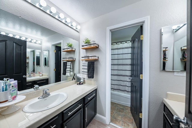 bathroom featuring shower / tub combo with curtain, vanity, and a textured ceiling