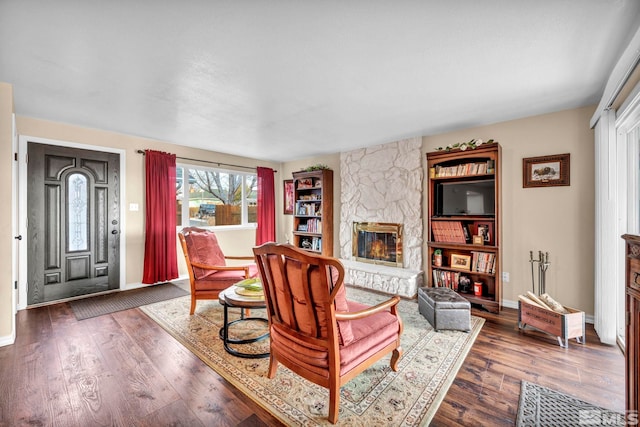 living room with dark hardwood / wood-style floors and a stone fireplace