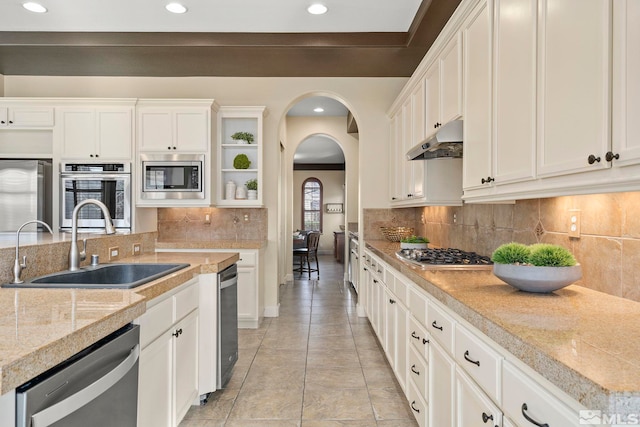 kitchen with light stone countertops, sink, backsplash, white cabinets, and appliances with stainless steel finishes