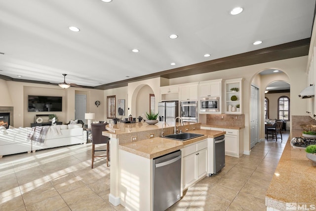 kitchen with a kitchen bar, stainless steel appliances, sink, a center island with sink, and white cabinets