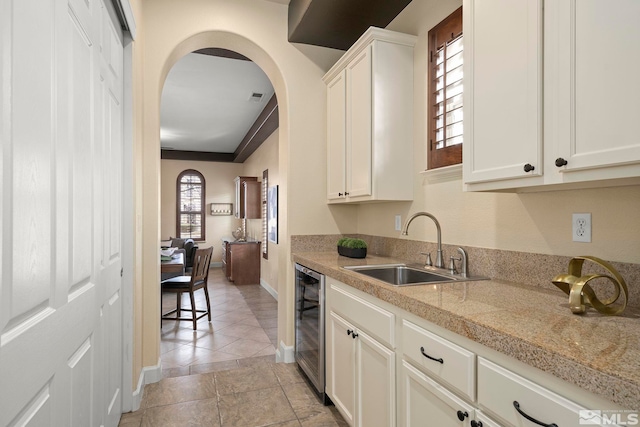 kitchen featuring white cabinetry, sink, light stone countertops, wine cooler, and light tile patterned flooring