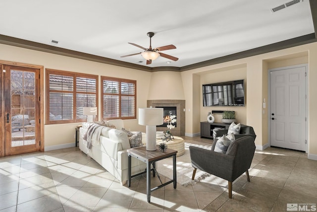 tiled living room with ceiling fan, ornamental molding, and a fireplace