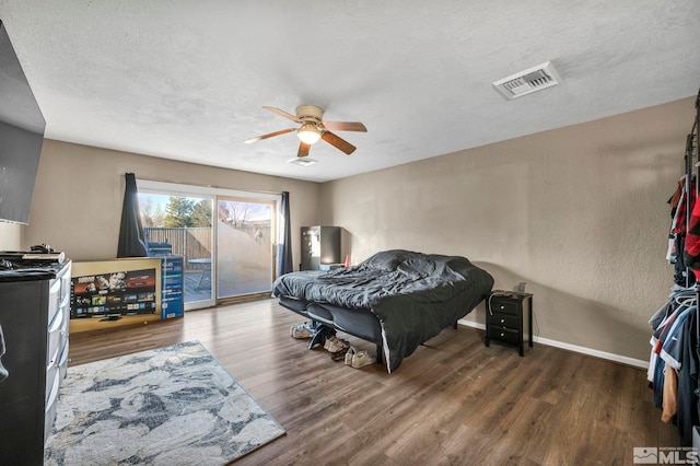 bedroom with access to exterior, a textured ceiling, dark hardwood / wood-style flooring, and ceiling fan