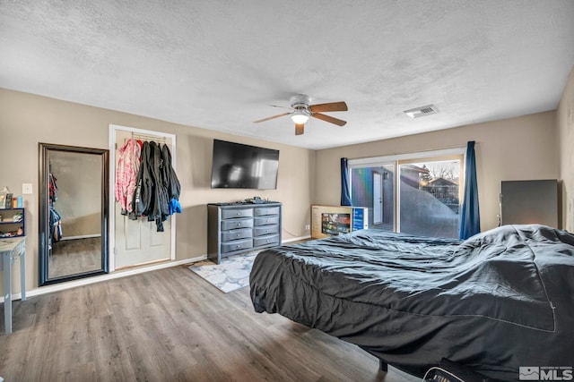 bedroom featuring a closet, a textured ceiling, hardwood / wood-style flooring, and ceiling fan