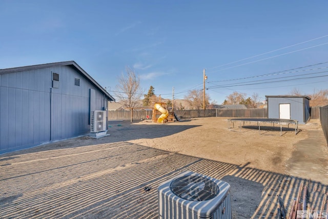 view of yard with a trampoline, a shed, a playground, and central air condition unit