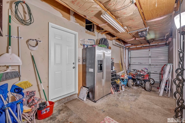 garage featuring a garage door opener and stainless steel refrigerator with ice dispenser