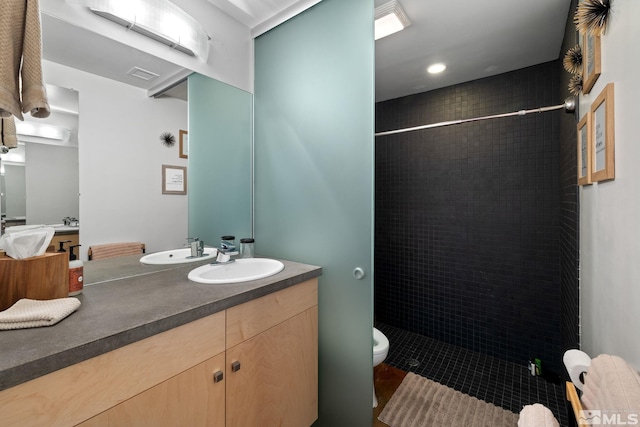 bathroom featuring tile patterned flooring, vanity, toilet, and tiled shower