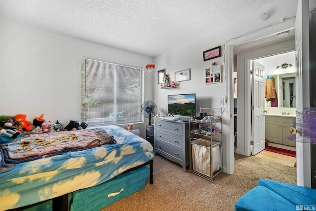 bedroom featuring connected bathroom, light carpet, sink, and a textured ceiling
