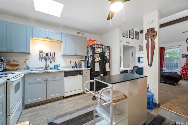 kitchen with a skylight, ceiling fan, sink, light colored carpet, and white appliances