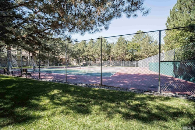 view of tennis court with a yard