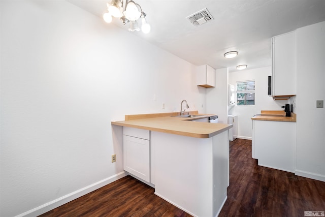 kitchen featuring sink, white cabinetry, dark wood-type flooring, and an inviting chandelier