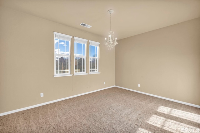 carpeted empty room featuring a notable chandelier