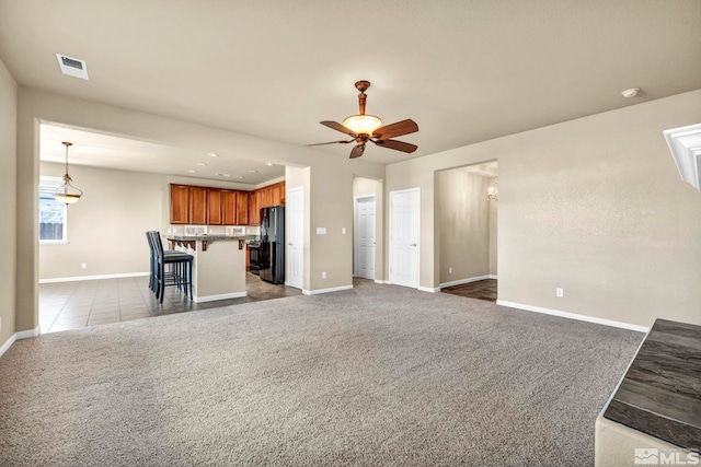 unfurnished living room featuring carpet floors and ceiling fan