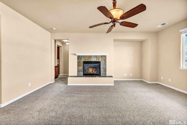 unfurnished living room with carpet, ceiling fan, and a tiled fireplace