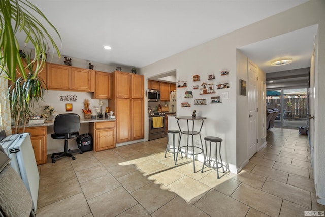 kitchen with radiator heating unit, stainless steel appliances, a breakfast bar area, light tile patterned floors, and built in desk