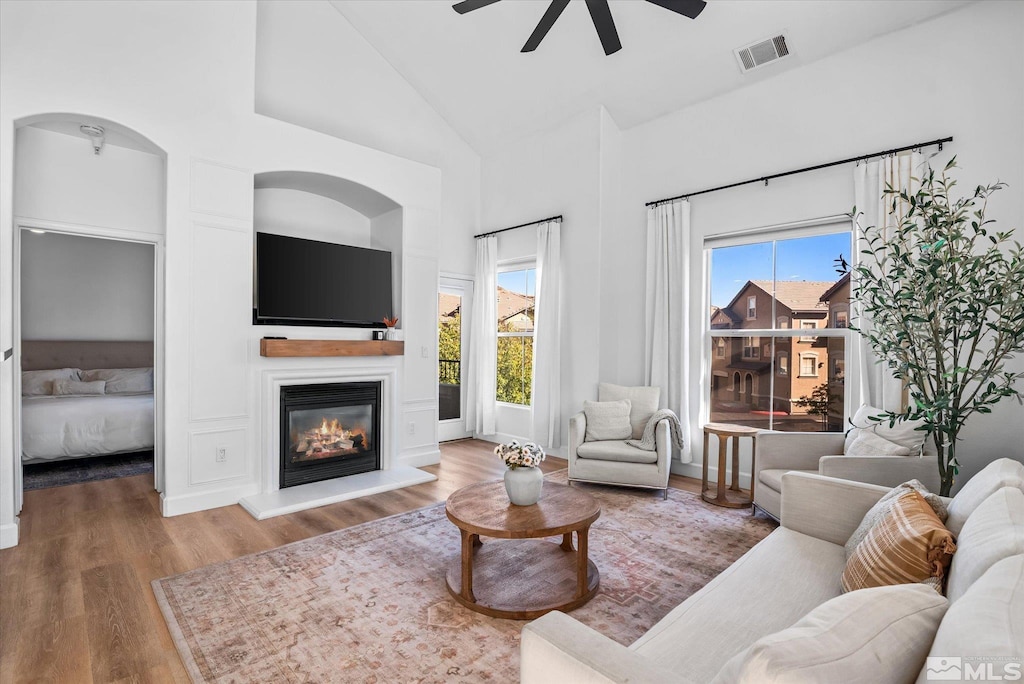 living room with ceiling fan, a wealth of natural light, high vaulted ceiling, and hardwood / wood-style flooring