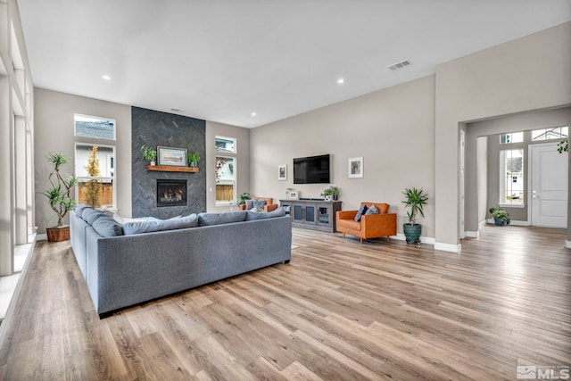 living area featuring light wood finished floors, visible vents, baseboards, recessed lighting, and a fireplace