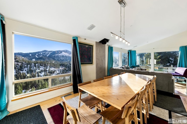 dining room with a mountain view, hardwood / wood-style flooring, and vaulted ceiling