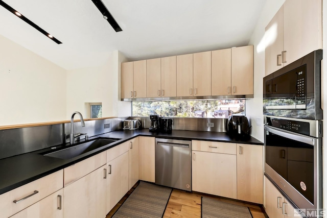 kitchen with cream cabinets, sink, decorative backsplash, light wood-type flooring, and stainless steel appliances