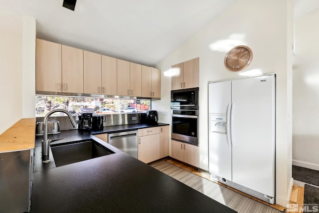 kitchen with sink, stainless steel appliances, vaulted ceiling, decorative backsplash, and light brown cabinetry