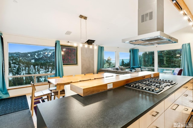 kitchen featuring white cabinetry, stainless steel gas cooktop, a mountain view, decorative light fixtures, and island range hood