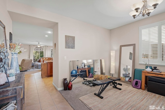 exercise area featuring light tile patterned floors and ceiling fan with notable chandelier