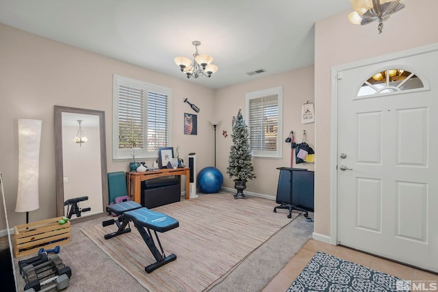 workout room with light tile patterned floors and a notable chandelier