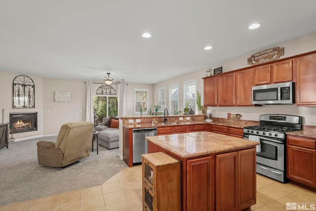 kitchen featuring kitchen peninsula, light carpet, stainless steel appliances, ceiling fan, and a kitchen island