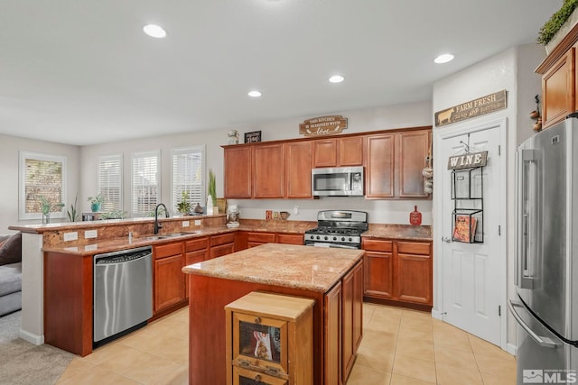 kitchen featuring sink, light tile patterned floors, kitchen peninsula, a kitchen island, and appliances with stainless steel finishes