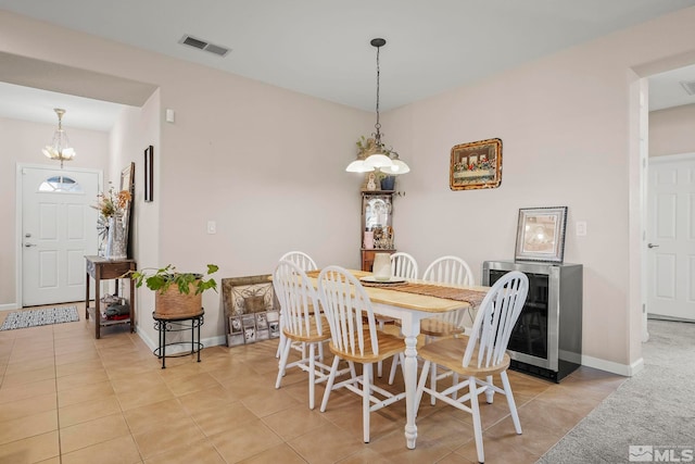 dining area featuring light tile patterned flooring, wine cooler, and an inviting chandelier