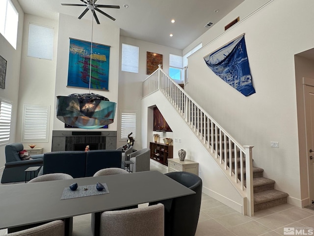 living room with a fireplace, light tile patterned flooring, a wealth of natural light, and ceiling fan