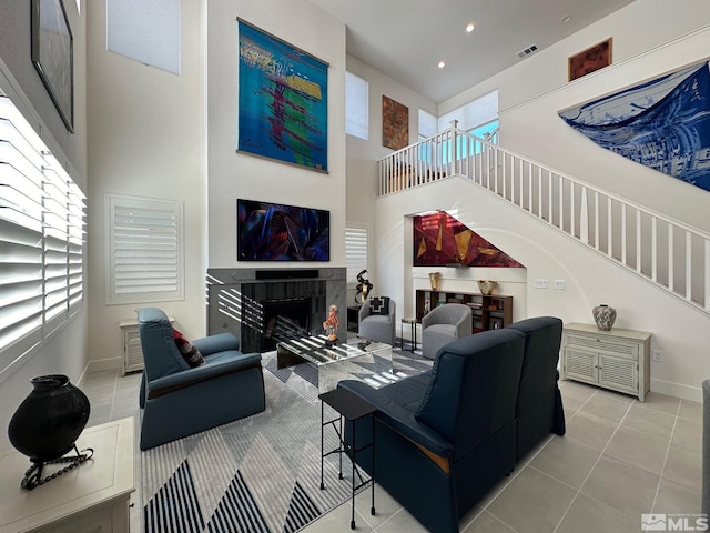 living room featuring light tile patterned flooring, a towering ceiling, and a fireplace