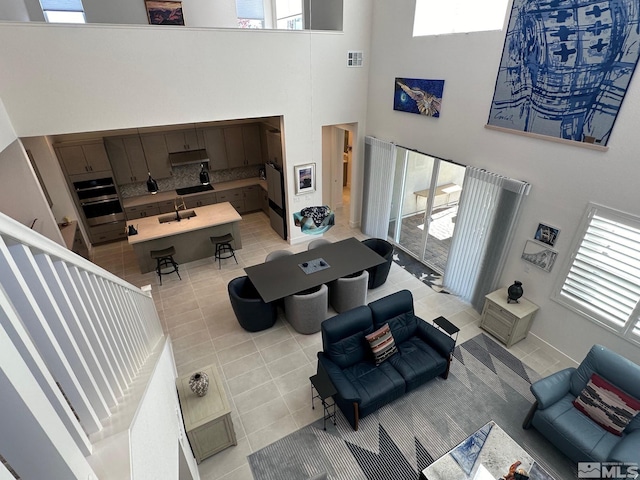 tiled living room with a healthy amount of sunlight, sink, and a high ceiling