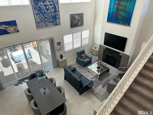 living room featuring a tile fireplace, tile patterned flooring, a towering ceiling, and a healthy amount of sunlight